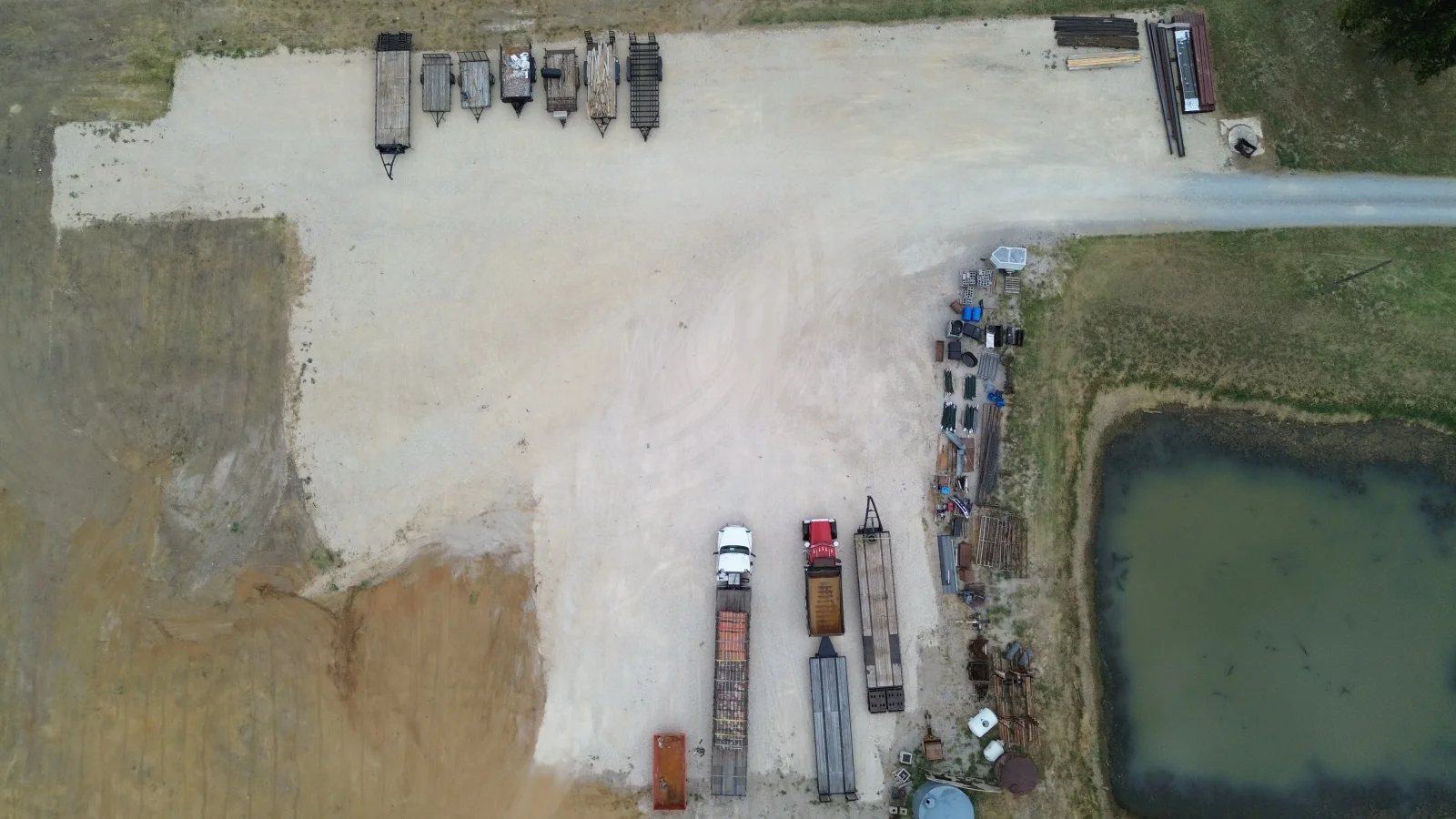 Aerial view of waterfront storage facility with boat docks, vehicles, and equipment staging on gravel lot